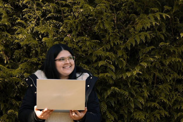 Foto mujer joven sosteniendo una computadora portátil mujer de trabajo de redes sociales en el parque