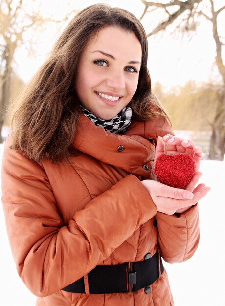 Mujer joven sosteniendo un corazón rojo en manos de