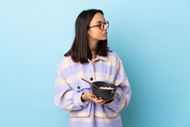 Mujer joven sosteniendo un cuenco lleno de fideos