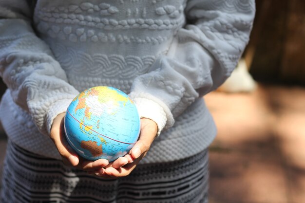 Foto una mujer joven sosteniendo un globo terráqueo con fondos de naturaleza handson