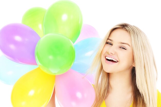 Una mujer joven sosteniendo globos sobre fondo blanco.