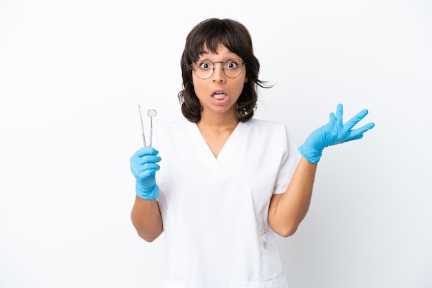 Foto mujer joven sosteniendo herramientas aisladas sobre fondo blanco con expresión facial sorpresa