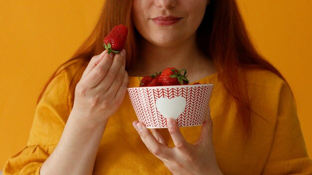 Mujer joven sosteniendo en las manos y da grandes fresas jugosas alimentos saludables