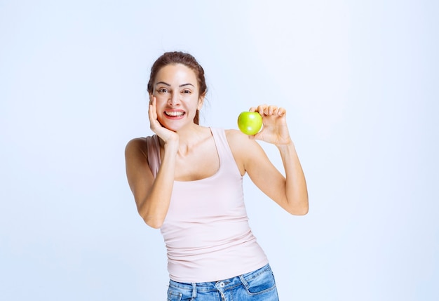 Mujer joven sosteniendo una manzana verde y pensando