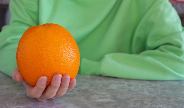 Mujer joven sosteniendo una naranja madura en la mano con espacio de copia. Concepto de estilo de vida saludable.