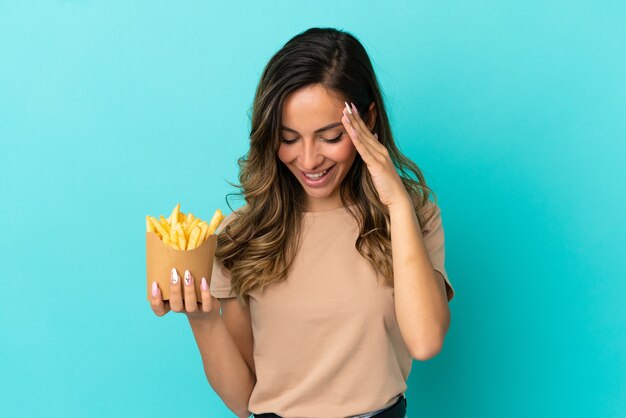 Mujer joven sosteniendo patatas fritas sobre fondo aislado riendo