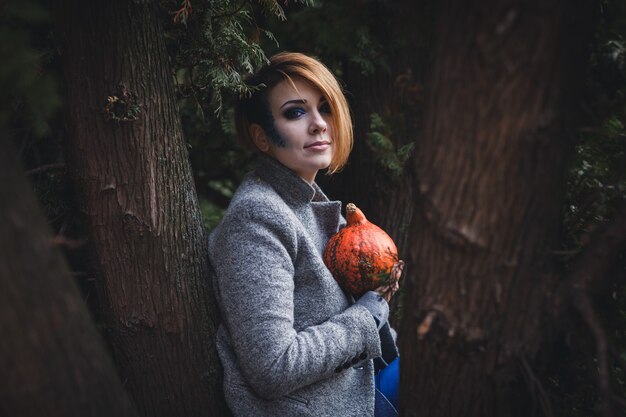 Mujer joven sosteniendo una pequeña calabaza.