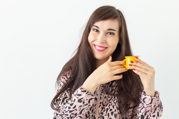 Mujer joven sosteniendo una pequeña taza amarilla de juguete en sus manos