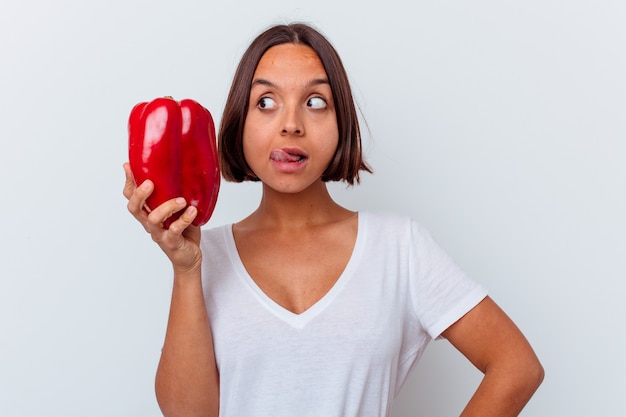 Mujer joven sosteniendo un pimiento aislado en la pared blanca