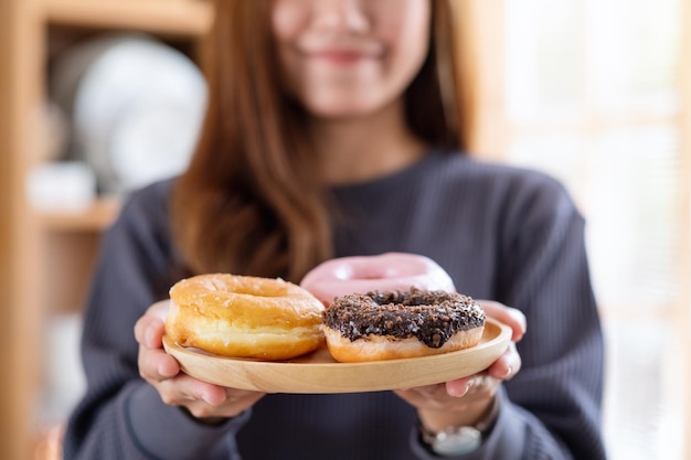 Una mujer joven sosteniendo un plato de donas en la cocina de casa