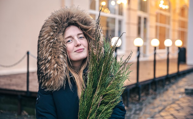 Una mujer joven sosteniendo ramas de thuja fondo borroso con luces bokeh