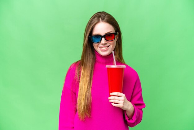 Mujer joven sosteniendo refresco mientras ve una película en 3D sonriendo mucho