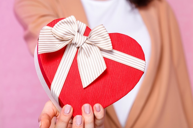 Mujer joven sosteniendo un regalo en forma de corazón