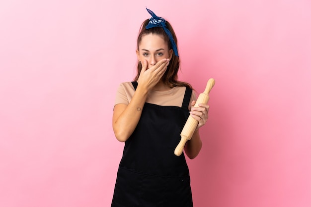 Mujer joven sosteniendo un rodillo cubriendo la boca con la mano