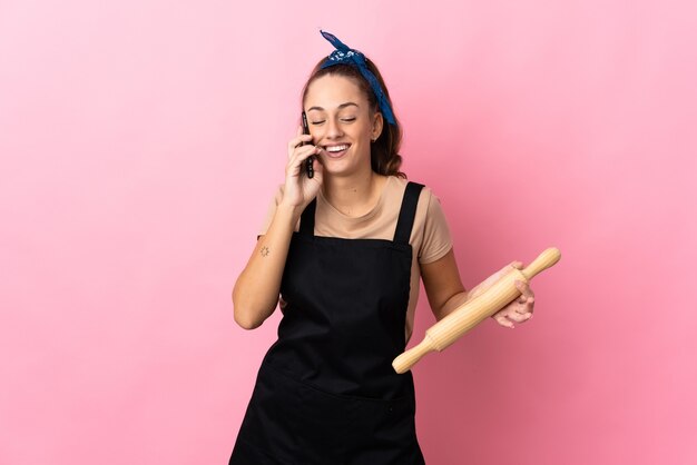 Mujer joven sosteniendo un rodillo manteniendo una conversación con el teléfono móvil con alguien