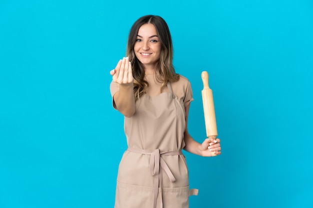 Mujer joven sosteniendo un rodillo posando aislado contra la pared en blanco