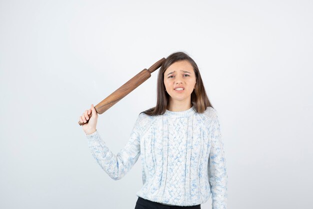 Mujer joven sosteniendo un rodillo sobre fondo blanco.