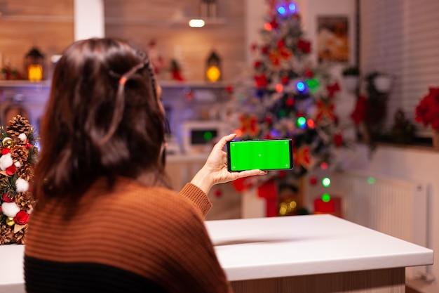 Mujer joven sosteniendo smartphone con pantalla verde