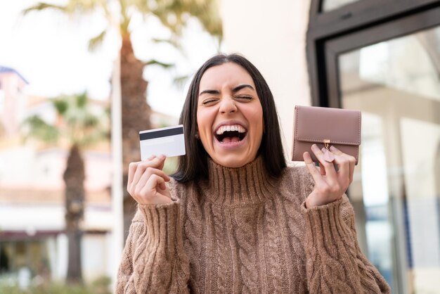 Foto mujer joven sosteniendo una tarjeta de crédito al aire libre