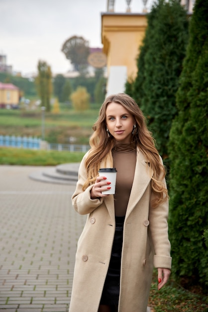 Mujer joven sosteniendo una taza de café caliente en el parque