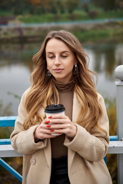 Mujer joven sosteniendo una taza de café caliente en el parque