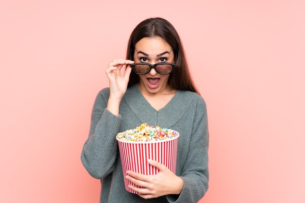 Mujer joven sosteniendo una taza de palomitas de maíz aislado