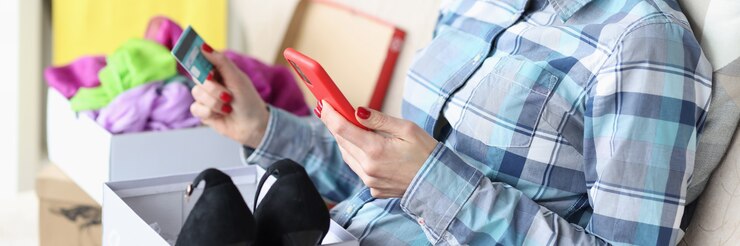 Foto mujer joven sosteniendo teléfono móvil y tarjeta de crédito en casa concepto de compras en línea