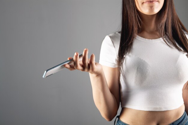 Mujer joven sosteniendo el teléfono sobre fondo gris