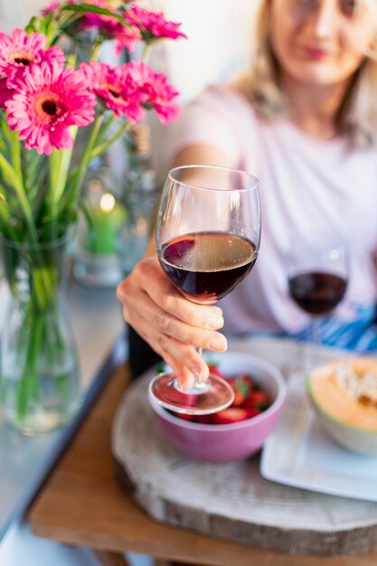 Foto mujer joven sosteniendo un vaso de vino mientras está sentada en la mesa en un restaurante