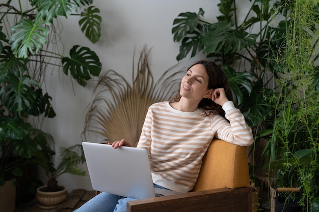 Mujer joven sostiene una computadora portátil en vueltas visualizando un buen futuro soñando con nuevas oportunidades de trabajo en proyectos