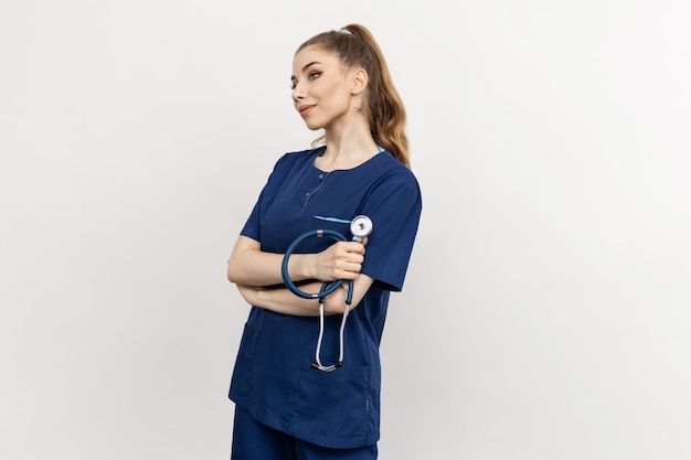 Una mujer joven sostiene un estetoscopio en la mano sobre un fondo blanco Retrato de estudio de un trabajador médico