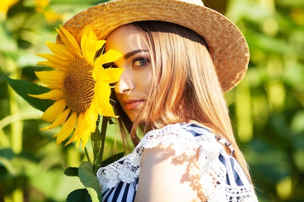 Una mujer joven sostiene un girasol en un campo floreciente de girasoles