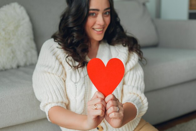 Foto una mujer joven sostiene una tarjeta de san valentín en forma de corazón. vacaciones. día de san valentín.