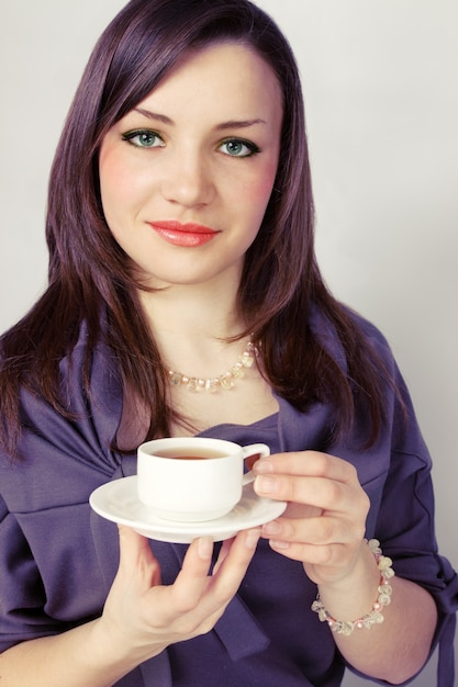 Mujer joven sostiene la taza con la bebida