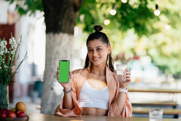 Mujer joven sostiene un teléfono inteligente con una pantalla verde