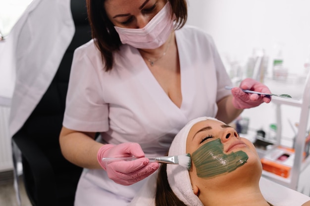 Mujer joven en un spa con mascarilla facial de algas