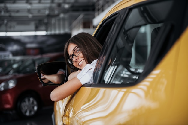 Mujer joven en su auto nuevo sonriendo