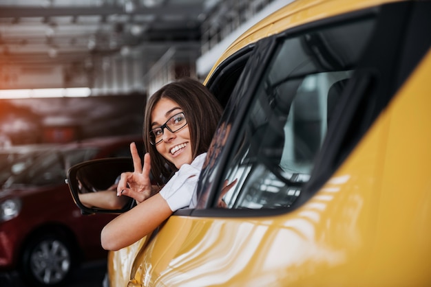 Foto mujer joven en su auto nuevo sonriendo