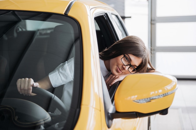 Mujer joven en su auto nuevo sonriendo