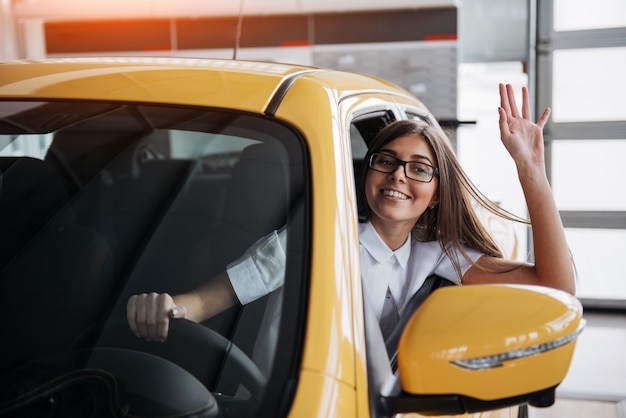 Mujer joven en su auto nuevo sonriendo