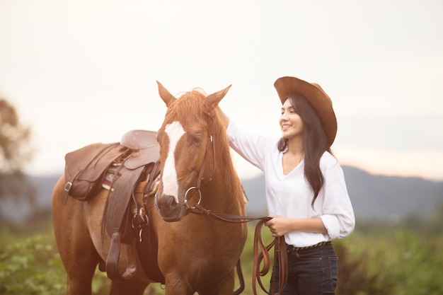 Foto mujer joven con su caballo en la luz del atardecer.