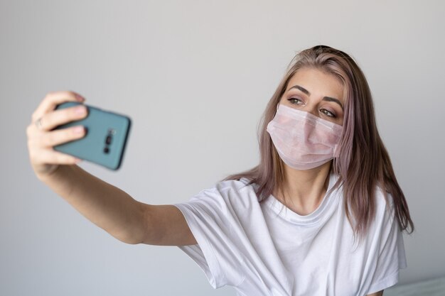 Foto mujer joven en su cama con una máscara protectora