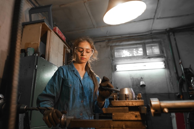 Foto mujer joven en su garaje trabaja en un torno profesión concepto turner metalmecánica torneado industria metal