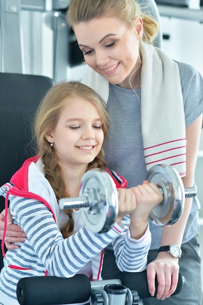 Mujer joven con su hija adolescente en un gimnasio con pesas