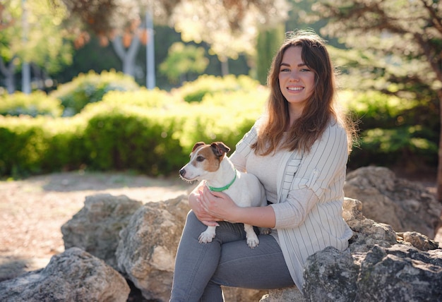 Mujer joven con su lindo Jack Russell Terrier al aire libre