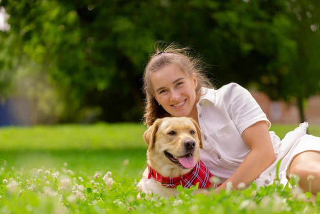 Mujer joven con su lindo labrador amarillo afuera Encantador concepto de amor animal de compañía