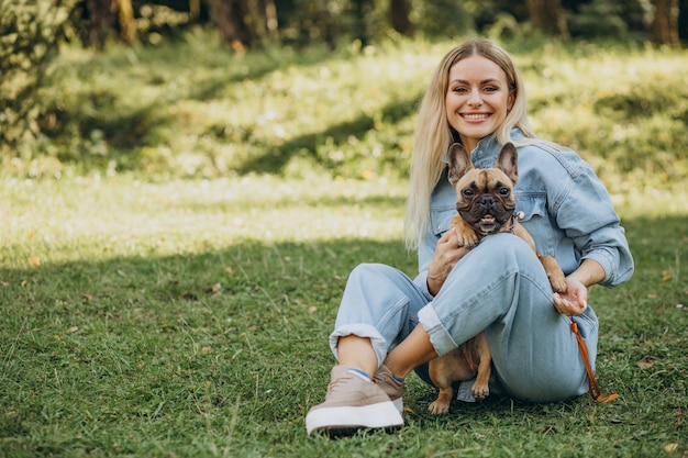 Mujer joven con su mascota bulldog francés en el parque