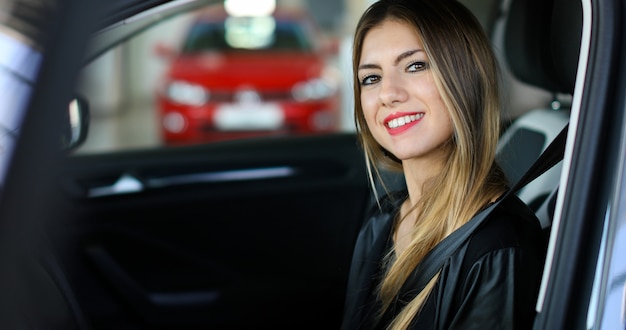 Mujer joven en su nuevo coche sonriendo