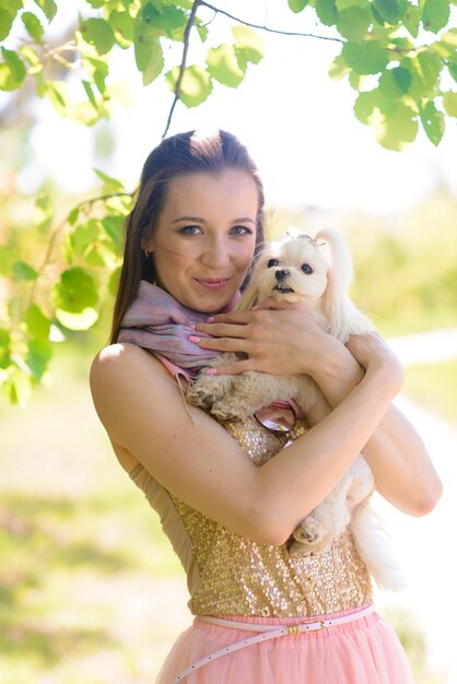 Foto mujer joven con su perro. cachorro de perro blanco con su dueño. concepto de amistad, animal y libertad.