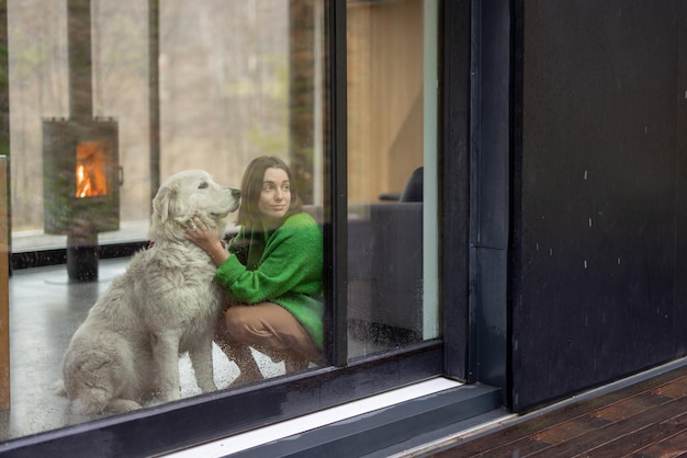 Mujer joven con su perro en casa moderna en la naturaleza